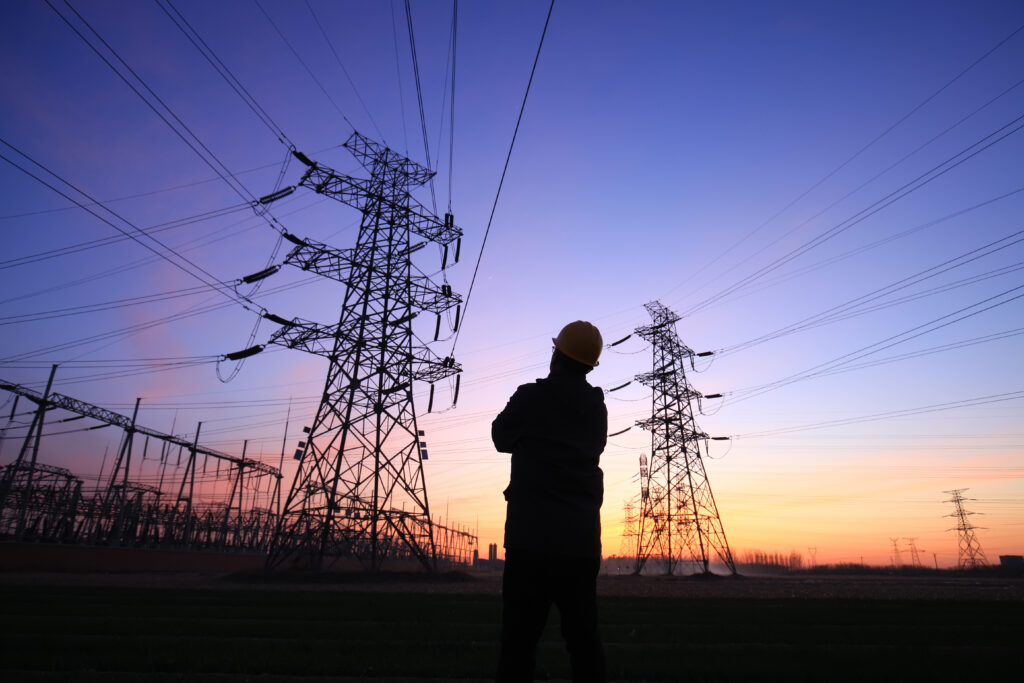 In the evening, electricity workers and pylon silhouette, Power workers at work